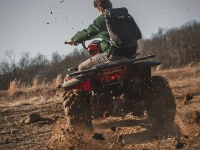 A person riding an ATV on a dirt trail, kicking up dust.
